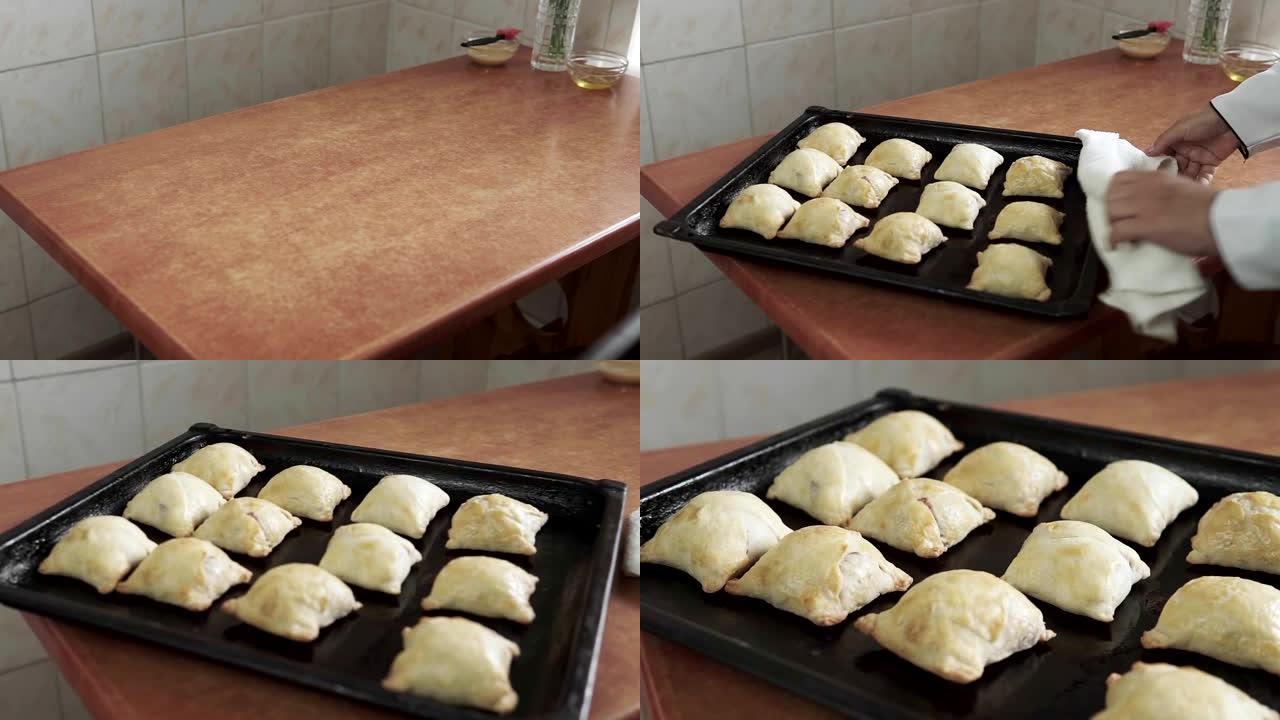 女性双手的特写镜头将烤盘上的热甜百吉饼和面包铺在盘子上，奶奶为家人自制烘烤。