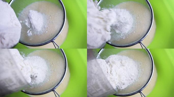 厨师将面粉通过金属筛子筛入装有鸡蛋，糖和牛奶的混合物的碗中。特写，时间流逝。做煎饼的过程。一系列框架