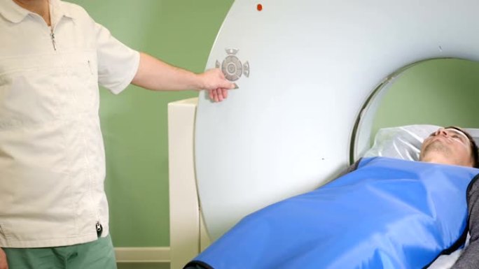 男性病人正在进行ct扫描。医疗设备:诊断门诊用计算机体层摄影机。健康的概念。医生按下CT MRI扫描