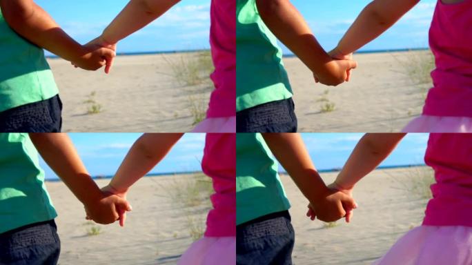 穿着粉红色裙子的小男孩和女孩在海滩上牵手的特写镜头