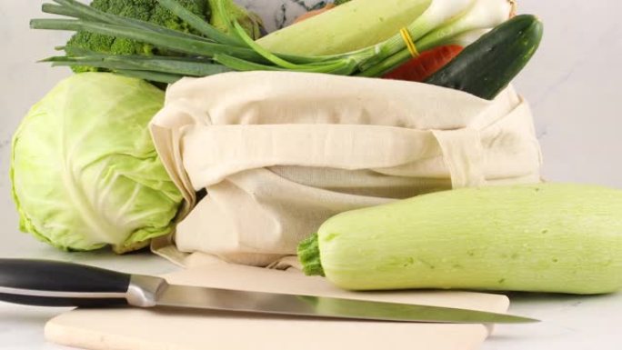 环保零废购物袋中的新鲜蔬菜和切菜板上的刀