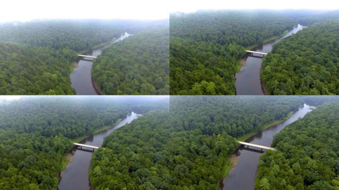 无人机在山区森林上朝着河水上的道路桥移动