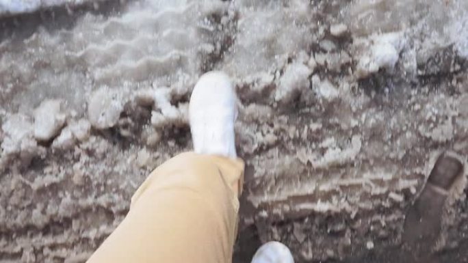穿着白色运动鞋的男人走在潮湿的雪地泥泞的道路上春天POV视频