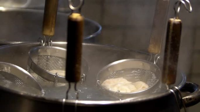 慢动作Jpanese厨师在火锅上用滤网汤煮饺子。