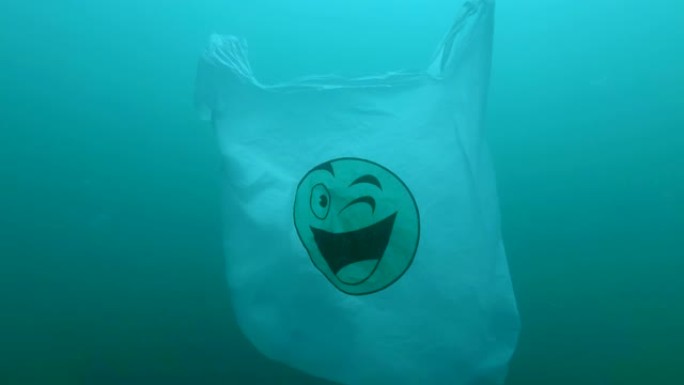 塑料污染，带有绿色笑脸的塑料袋在水下慢慢漂移。水下塑料碎片。塑料垃圾环境污染问题