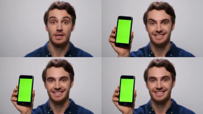 男子展示绿屏智能手机。带色度键的男性展示手机