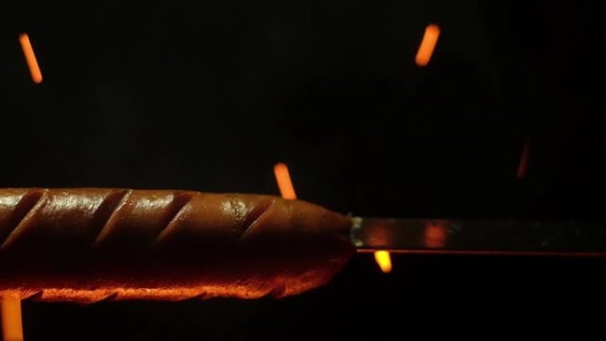 火火焰和火花背景下的金属串上的油炸香肠