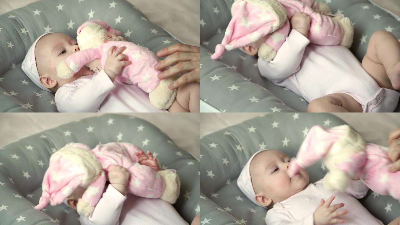 4个月大的小女孩的肖像躺在婴儿床里，玩泰迪熊玩具。父亲的手玩小女儿毛绒玩具。幸福的家庭和关怀的理念