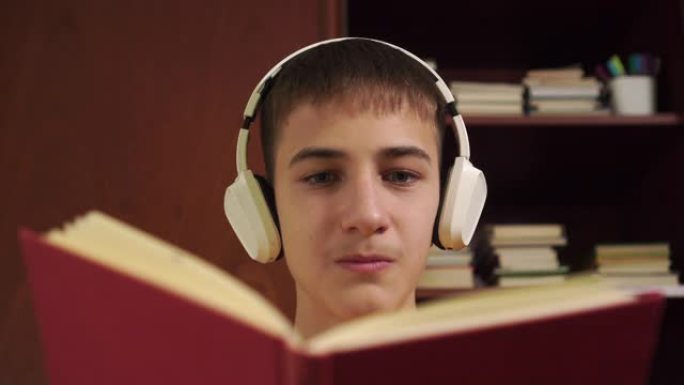 年轻的学生在木制书柜的背景下大声朗读一本书