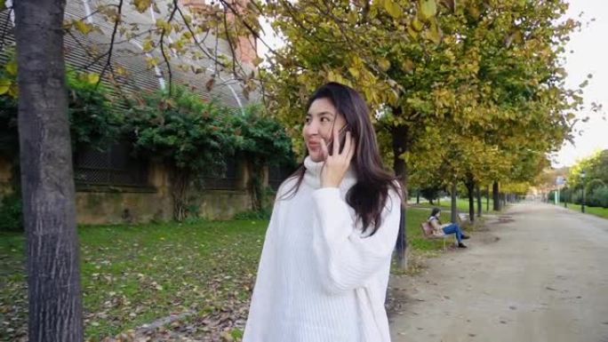 亚洲年轻女学生在电话上讲话并微笑