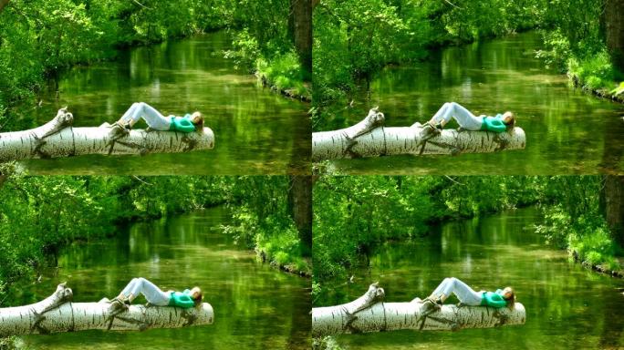 年轻女子独自在森林河上的原木上休息