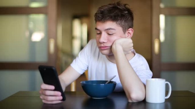 青少年在早餐时用智能手机在一盘粥上发短信
