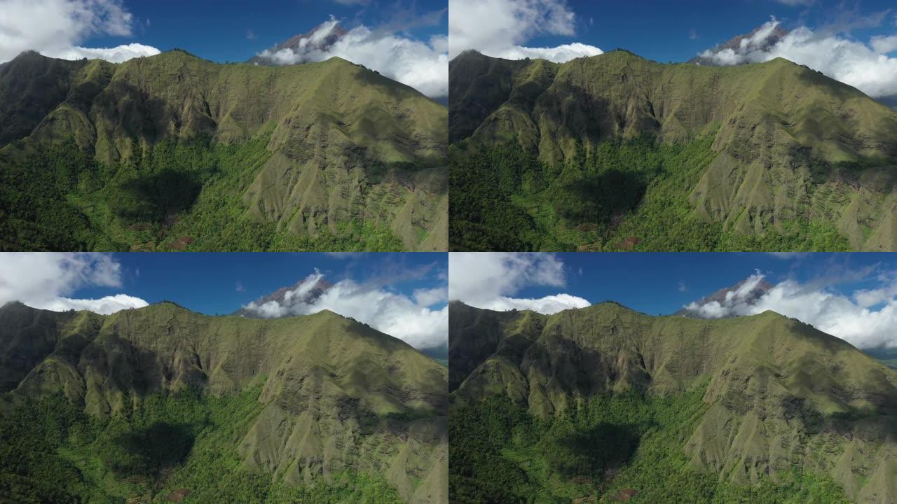 从上方可以看到，令人惊叹的鸟瞰图是绿色的山脉，背景是云彩和美丽的蓝天。印度尼西亚西努沙登加拉省龙目岛