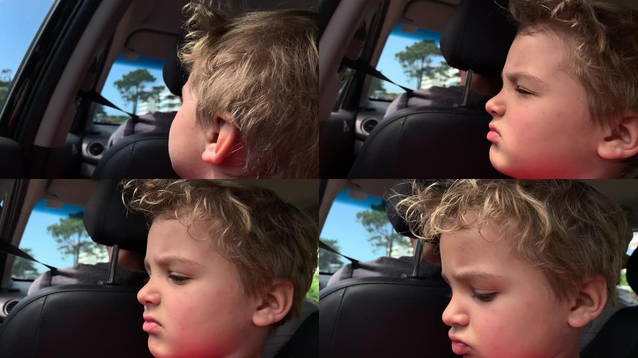儿童男孩蹒跚学步，坐在汽车后座上，看着窗外