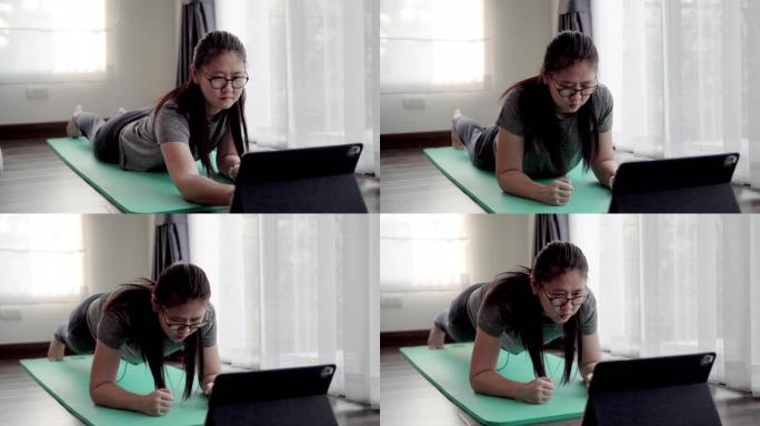 亚洲妇女在新型冠状病毒肺炎病毒检疫用数字平板电脑在家锻炼。