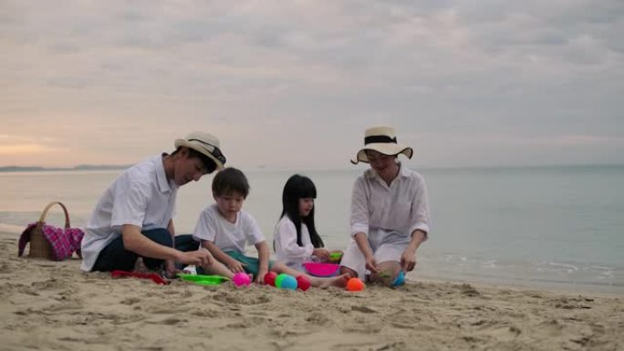 亚洲家庭度假在沙滩上玩耍，一起堆沙子。
