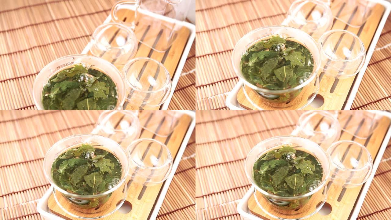 将热绿茶倒入玻璃碗中。特写