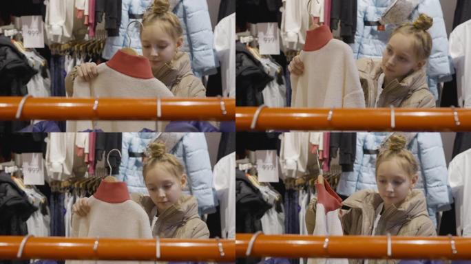 购物时服装陈列室里的年轻少女看夹克。年轻女子在时尚精品店挑选衣服。少女在服装店购物。