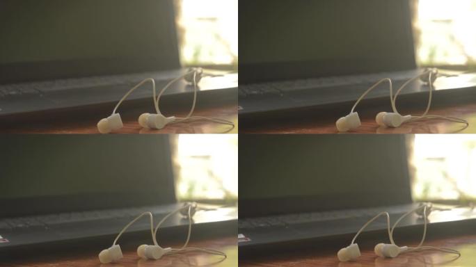 耳机的特写镜头 (耳塞插孔)，用于在便携式设备上听音乐和声音。背景电脑笔记本电脑显示器。物联网，现代