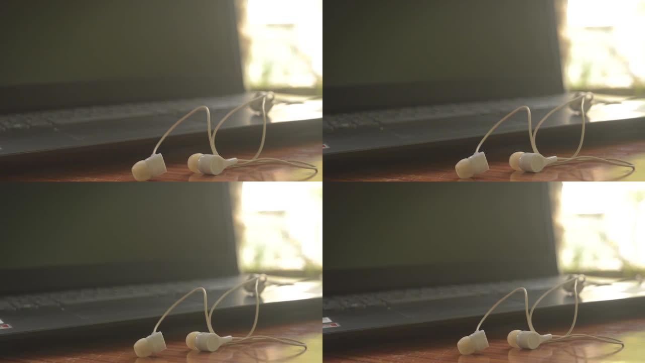 耳机的特写镜头 (耳塞插孔)，用于在便携式设备上听音乐和声音。背景电脑笔记本电脑显示器。物联网，现代