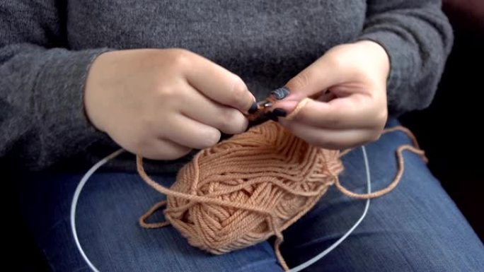 用彩色羊毛编织的女性手。手工编织