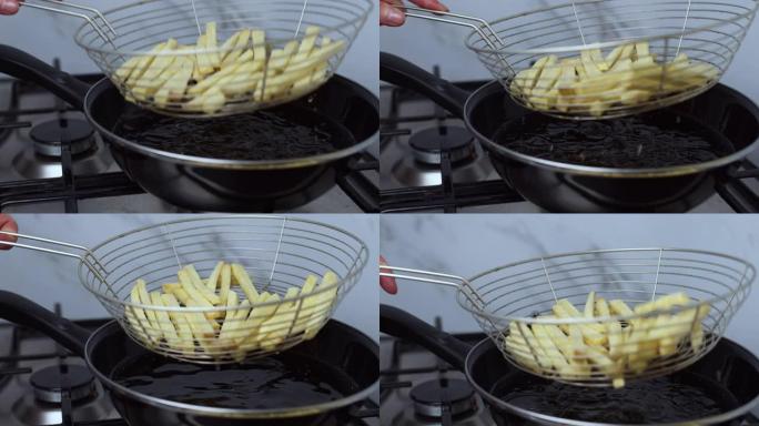 特写镜头，取出/取出自制薯条，并从煤气炉平底锅的篮子里的沸腾油中排出。煮熟的薯条上有很多气泡。