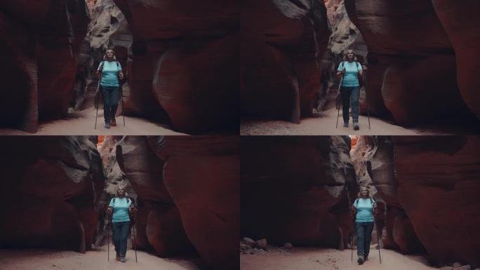 游客在带有橙色岩石的深槽峡谷的干燥河床上徒步旅行