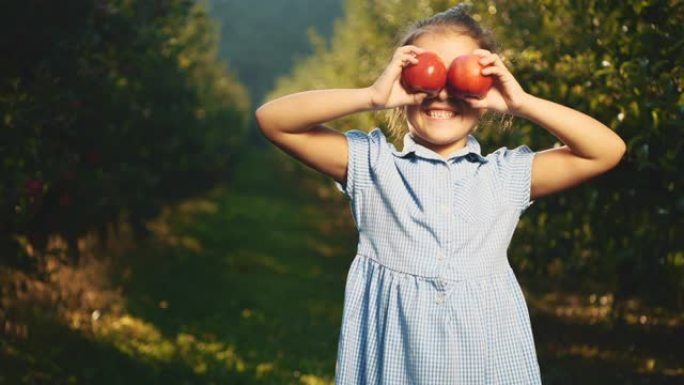 小女孩在户外用红苹果模仿她的眼睛。女孩笑得很开心。复制空间。4K。