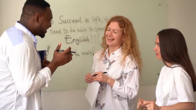 多民族快乐的学生和黑人老师学习外语，并在课堂上一起微笑和大笑。用笔记本电脑学习。黑人帅哥学生和白人一