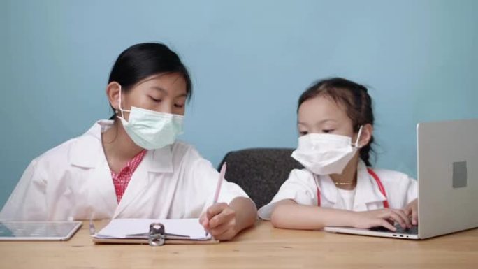亚洲医生女孩使用蓝色背景的笔记本电脑。