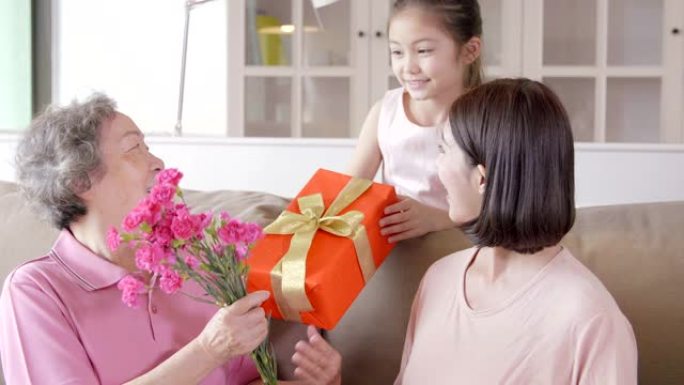 母亲节快乐。孩子和母亲祝贺祖母送花和礼品盒