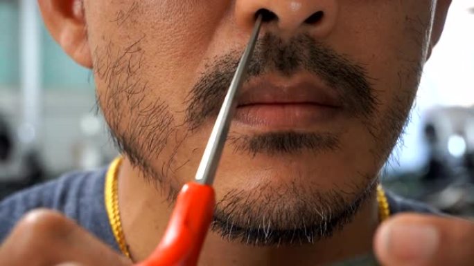 一个人用一把剪刀修剪胡须。
