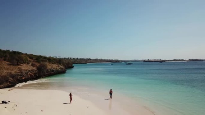 一对夫妇走在龙目岛粉红海滩的海岸线上。这个地方是一个隐藏的宝石，没有被游客宠坏。孤独和平静的感觉，波