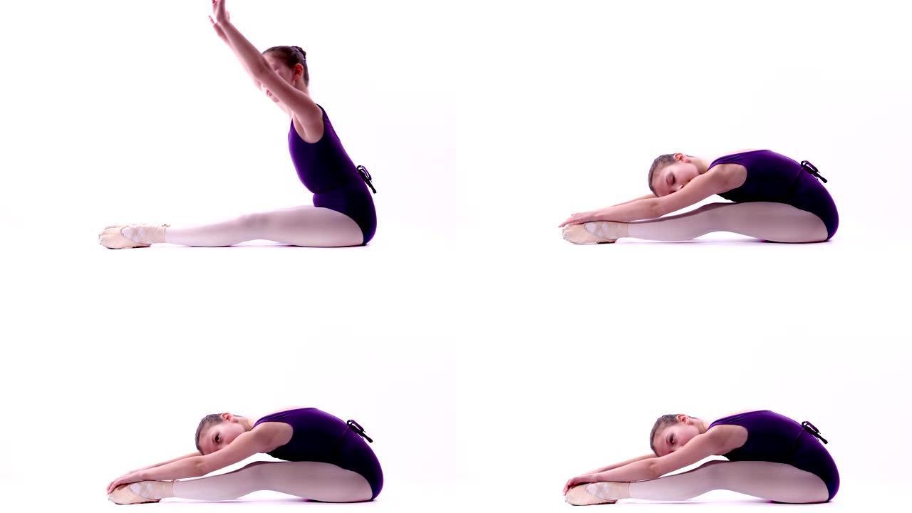 年轻的芭蕾舞演员坐在地板上锻炼身体。女孩在芭蕾舞课上伸展双腿，孤立在白色背景上。舞蹈课上的女孩