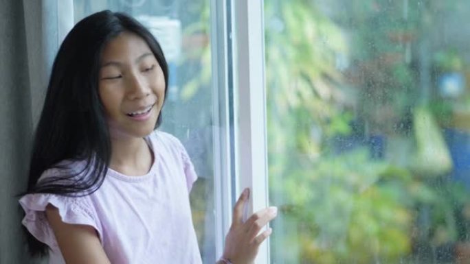 亚洲女孩在雨天看着窗外，慢动作。