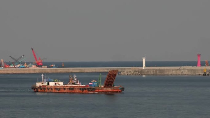 一艘生锈的旧驳船漂浮在韩国东河港口的一个海湾上