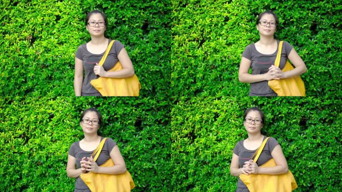 绿色叶子背景上的黄色棉布袋亚洲女人。