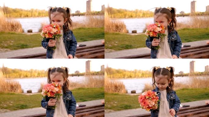 小女孩坐在公园的长椅上，摆着一束鲜花，她嗅着鲜花。