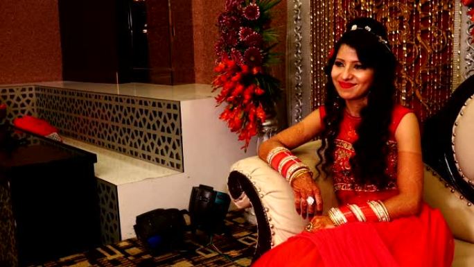 美丽的年轻印度新娘坐在婚礼接待厅的豪华沙发上