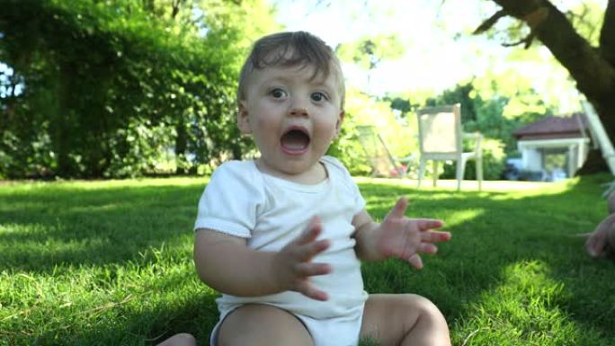 快乐的宝宝在户外花园里拍手，快乐的英俊蹒跚学步的孩子拍手