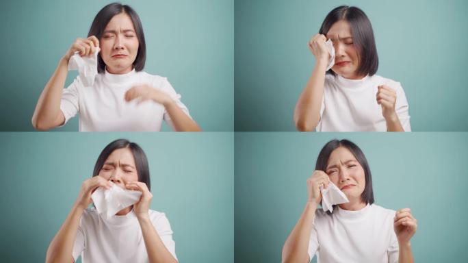亚洲女人悲伤而哭泣，站在蓝色背景上孤立。4k视频。情感概念。
