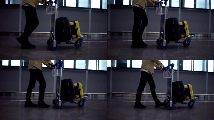 国际机场内带行李车的无法辨认的男性乘客。匆忙散步，侧视图