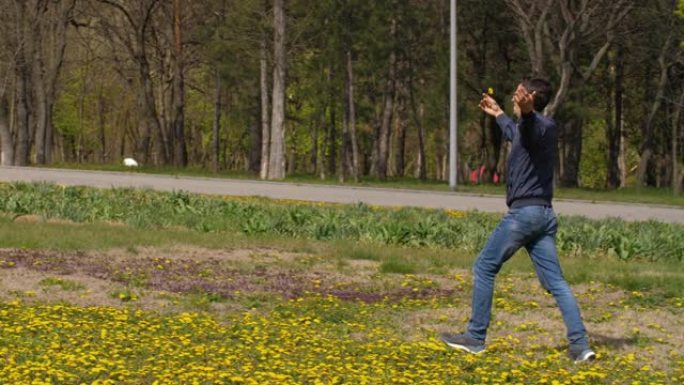 有趣的快乐男人带着一朵花穿过草地
