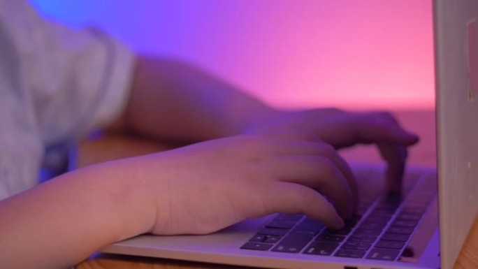 用手打字笔记本电脑与led紫色光背景。