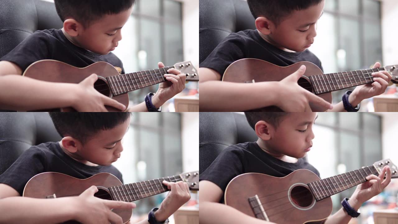 可爱的男孩在家里学习演奏夏威夷四弦琴。