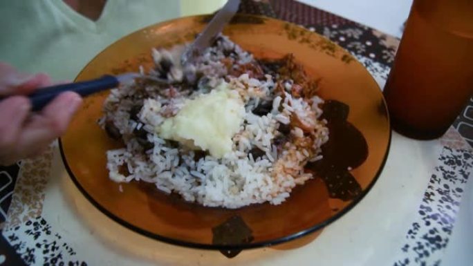 巴西老年妇女吃豆和米饭配鸡肉。在盘子上特写。