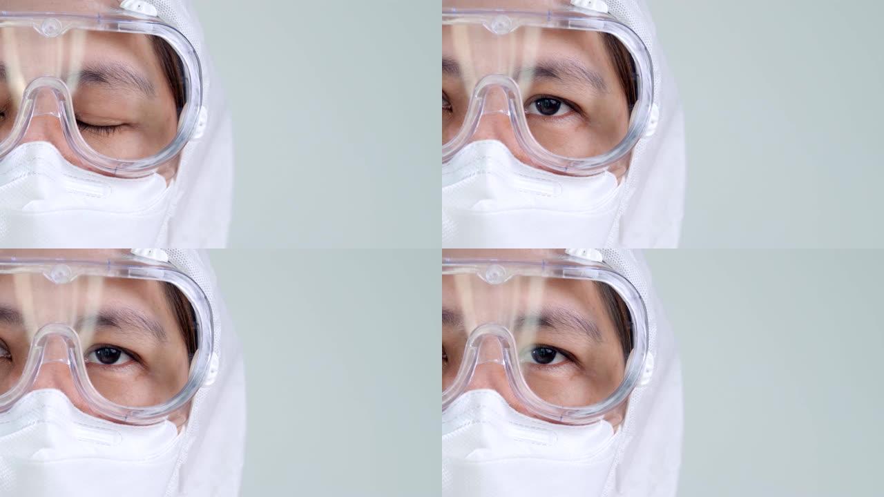 穿着防护危险品PPE套装戴着口罩和眼镜的亚洲医生睁开眼睛，有复制空间