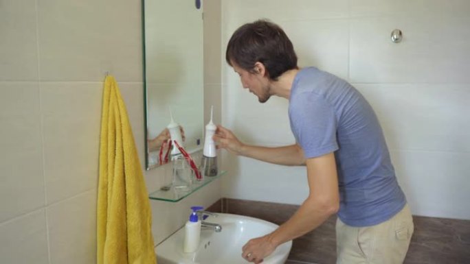 一名年轻人使用便携式水牙线器牙科口腔冲洗器清洁牙齿