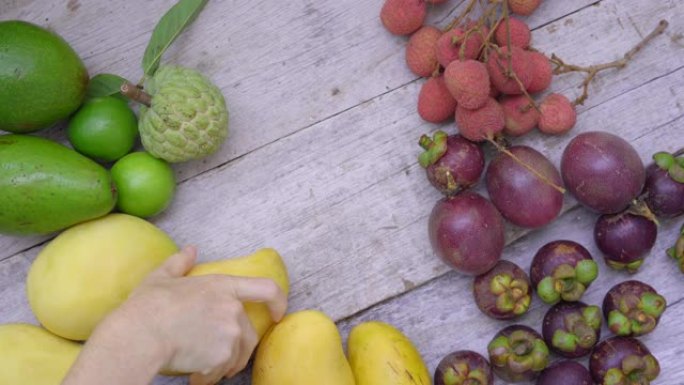 女人从装满热带水果的木桌上拿走水果