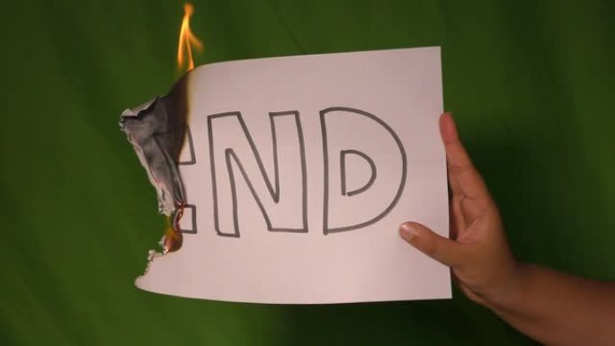 一只手握着燃烧的纸，上面写着文字。